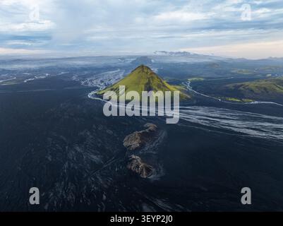 Blick aus der Vogelperspektive auf den Vulkan Maelifell mit seinen lebhaften moosigen grünen Hängen, die aus den riesigen schwarzen vulkanischen Sandebenen und Gletscherflüssen in Skaftarhrep ragen Stockfoto
