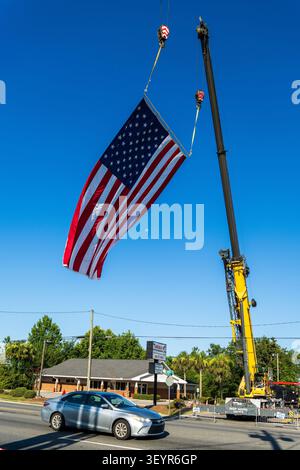 Lynn Haven, FL, USA. Juli 2026. Ein Deep South Cranes Grove Kran hebt in den frühen Morgenstunden eine riesige amerikanische Flagge hoch über der Ohio Avenue, während Lynn Haven sich auf die jährliche Feier zum 4. Juli vorbereitet. Die Flaggenausstellung eröffnet Freedom by the Bay, die den 250. Geburtstag Amerikas feiert, mit einer Parade um 8:45 UHR, gefolgt von einem Abend im A.L. Kinsaul Park in North Bay mit Live-Musik von Taydee Marie und Georgia Southern Rockern The Band Waleska, Food Trucks und Feuerwerk nach Sonnenuntergang. Quelle: Tosh Persons / Alamy Live News Stockfoto