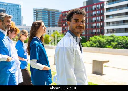 Verschiedene Gruppen von Gesundheitsfachleuten, darunter Ärzte und Krankenschwestern, die draußen stehen und medizinische Teamarbeit, Fachwissen und Engagement in repräsentieren Stockfoto