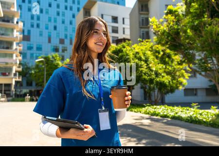 Lächelnde weibliche Gesundheitsfachkraft, die Kaffee und Tablet hält Stockfoto
