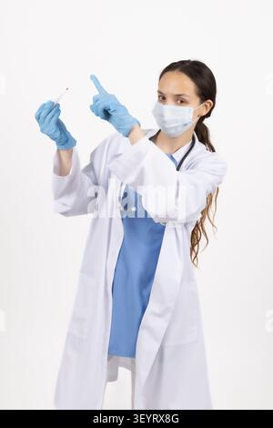 Ärztin in Schutzmaske, die mit dem Finger nach oben zeigt Stockfoto