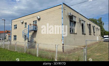 Hinter einem C befindet sich eine moderne, helle Backsteinindustrie mit einer Metalltreppe, mehreren Fenstern und einer Außenklimaanlage Stockfoto