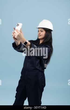 Ingenieurin in mit Schutzhelm, die Fotos auf dem Smartphone in einem professionellen Foto macht... Stockfoto