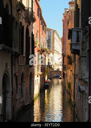 Malerischer schmaler Kanal in Venedig, gesäumt von farbenfrohen historischen Gebäuden und vertäuten Booten Stockfoto