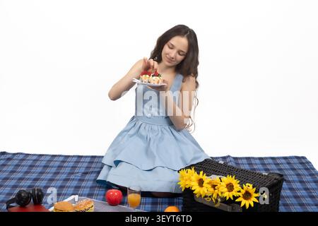 Eine junge Frau, die Reisekoffer auf dem Boden in einem professionellen Fotostud packt... Stockfoto