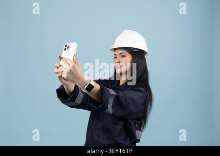Junge Arbeitnehmerin macht Selfie im Hardhat in einem professionellen Fotostudio e... Stockfoto