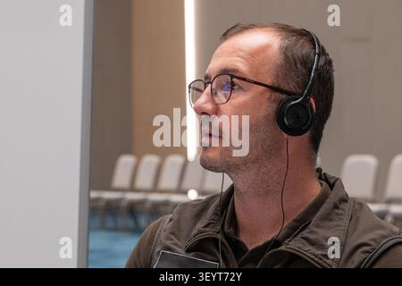 Ein Nahaufnahme-Porträt, von der Seite aufgenommen, eines männlichen Teilnehmers, der bei der Konferenz Kopfhörer für Simultandolmetschen trägt Stockfoto