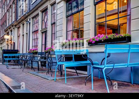 Gartenbestuhlung eines Cafés entlang einer ruhigen Straße im Zentrum von Amsterdam, Niederlande. Stockfoto