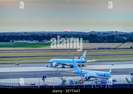 Passagierflugzeug rollt auf dem Amsterdam Airport Schiphol während des Sonnenuntergangs in Amsterdam, Niederlande, vor. Stockfoto