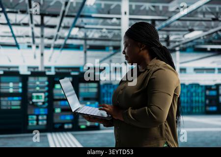 Frau in der Servereinrichtung, die Tests an der Infrastruktur durchführt und mit Software arbeitet, um Fehler zu beheben. Stockfoto