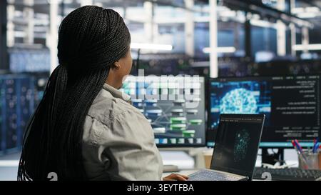 Der Administrator des Rechenzentrums verwendet einen Laptop, um Workloads des maschinellen Lernens zu verwalten, wobei er mit KI-Technologie und Hochleistungssystemen arbeitet. Stockfoto