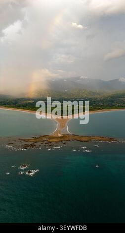 Walschwanzsandbar, die eine einzigartige natürliche Landschaft am Uvita Beach in costa rica mit einem farbenfrohen Regenbogen über den Bergen bildet Stockfoto