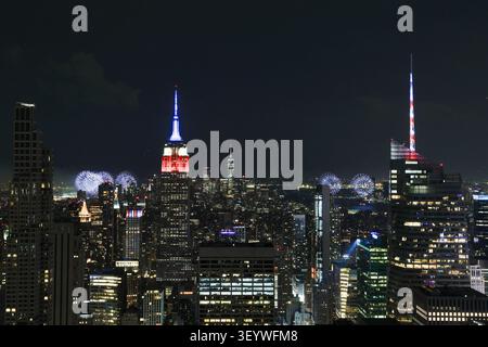 New York, United States. 04th July, 2026. The Empire State Building is lit in red, white and blue as the Macy's 4th of July fireworks light up the night sky as part of the celebration of America's 250th anniversary as seen From the Top of the Rock Observation Deck at Rockefeller Center in New York City on Saturday, July 4, 2026. Photo by John Angelillo/UPI Credit: UPI/Alamy Live News Stockfoto