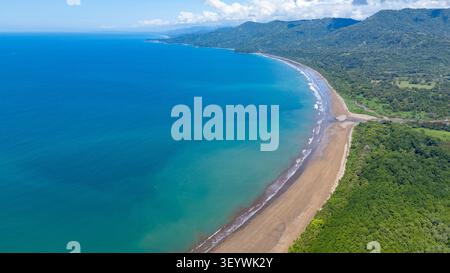 Uvita Beach in costa rica präsentiert seine einzigartige Form, wo ein Fluss auf den pazifischen Ozean trifft, eingerahmt von üppigem Regenwald Stockfoto