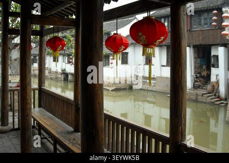 SEENISCHER AUSBLICK AUF TRADITIONELLE UFERHAUSEN UND EINEN KANAL, EINGERAHMT VON EINEM HOLZPAVILLON IN DER ANTIKEN STADT ZHUJIAJIAO, SHANGHAI, CHINA Stockfoto