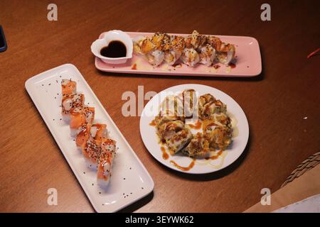 Japanische Sushi-Rolle auf schwarzer Schieferplatte auf hölzernem Hintergrund Stockfoto