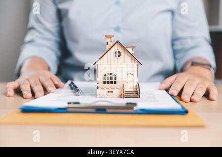 Vertragskonzept mit Hauseigentum auf unterschriebenen Dokumenten, Stift und Schreibtisch, ideal für Immobilienverkäufe, Hypothekenverträge und Immobilien Stockfoto