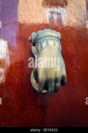 Ein detaillierter Türgriff aus Vintage-Bronze zeigt die Form einer Frauenhand. Dieses einzigartige Stück verleiht der Holztür Charakter und zeigt das antike cr Stockfoto