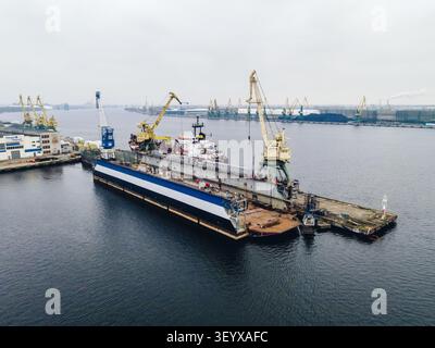 Riga, Lettland - 03. November 2021: Luftaufnahme einer Werft im Hafen von Riga mit einem schwimmenden Trockendock mit einem Schiff, das in Reparatur ist und von YE bedient wird Stockfoto