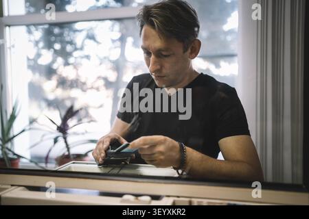 Kunde Mann, der mit Kreditkarte an einem Terminal im Innenbereich bezahlt, Der Käufer bezahlt den Einkauf mit einer Kreditkarte. Stockfoto