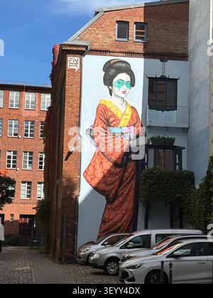 Ein großes, farbenfrohes Straßenkunst-Mural einer japanischen Frau in einem Kimono, gemalt auf einer Backsteinmauer in Berlin, Deutschland Stockfoto