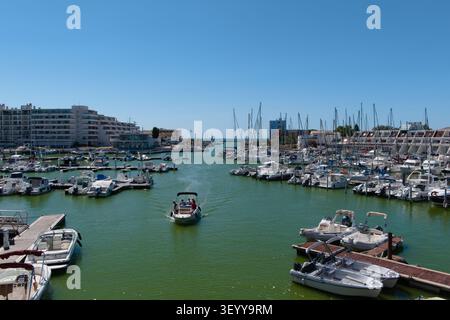 Aus der Vogelperspektive auf den geschäftigen Yachthafen von Carnon mit einem Motorboot, das durch den Kanal segelt und Yachten an einem sonnigen Tag in Südfrankreich anlegt. Stockfoto
