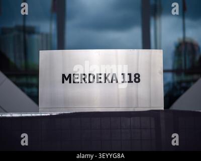 Metallschild mit dem Text Merdeka 118 mit einem modernen Glasgebäude in Kuala Lumpur, Malaysia Stockfoto