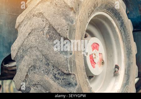 Großer schwerer schwarzer Gummireifen. Alte eisengraue Scheibe. Hinterrad landwirtschaftlicher Maschinen. Nahaufnahme Stockfoto