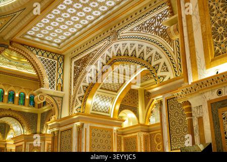 Horizontale Tiefenaufnahmung im Innenraum der prächtigen Großen Halle im Präsidentenpalast Qasr Al Watan, islamische Architektur mit aufragenden goldenen Bögen. Stockfoto