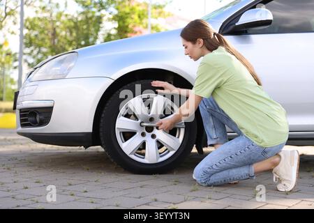 Frau wechselte im Auto draußen an sonnigem Tag den Reifen Stockfoto