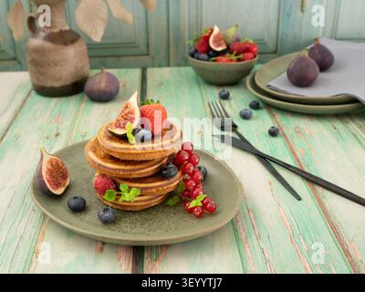 Im Stil gehaltene Frühstücksszene mit flauschigen Pfannkuchen mit Feigen, Beeren und Obst der Saison Stockfoto