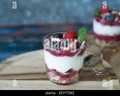 Mehrschichtiges Frühstücksparfait mit Joghurt, Chiasamen, Beeren und knusprigem Müsli, serviert in einem Glas Stockfoto