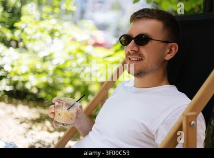 Ein Typ trinkt kalten Kaffee bei heißem Sommerwetter. Stockfoto