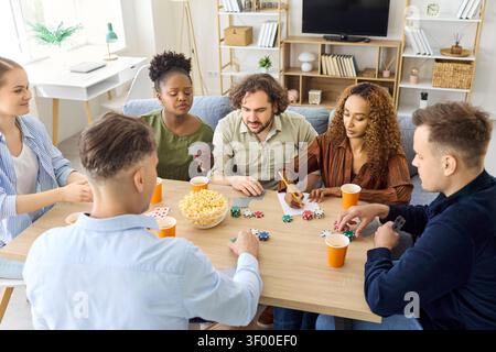 Gemischte Gruppe von Freunden, die zu Hause während entspannter Spielabende im Haus Karten spielen Stockfoto