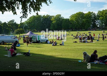 Sonniger Tag in einem öffentlichen Park mit Menschen, die auf der Wiese entspannen Stockfoto