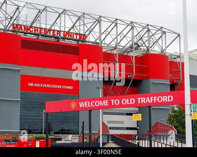 Manchester, Großbritannien, 4. Juli 2026: Das alte Trafford-Stadion mit seiner berühmten roten Fassade und Schildern steht unter einem bewölkten Himmel und repräsentiert die Geschichte des Fußballsports Stockfoto