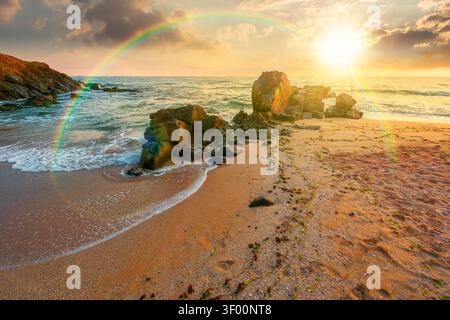 Sonnenuntergang über riesigen Steinen am Sandstrand. Wunderbarer Urlaub am Meer. Wolken am blauen Himmel über dem Horizont. Blick auf die Wellen Washin Stockfoto