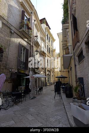 Gebäude mit Steinmauern und traditioneller Architektur, die eine enge Gasse in baris Altstadt säumen, mit mehreren Cafés im Freien, die für die Sommerabende bereit sind Stockfoto