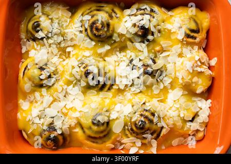 Hausgemachte Zimtrollen mit würzigem Zitronenquark und Mandelscheiben. Frisch gebackene Gebäckstücke, perfekt zum Frühstück oder für einen köstlichen Leckerbissen im Stockfoto