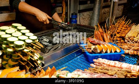 Ein lebhafter Street Food Stand auf dem Shilin Night Market in Taipei, Taiwan, bietet eine Vielzahl von Köstlichkeiten mit Spießen. Das Array enthält Zucchini und Diff Stockfoto