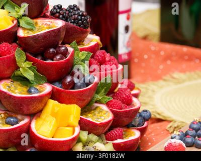 Buntes Display mit frischen Früchten wie Passionsfrucht, Beeren, Mango und Minze bei einer Catered-Veranstaltung Stockfoto