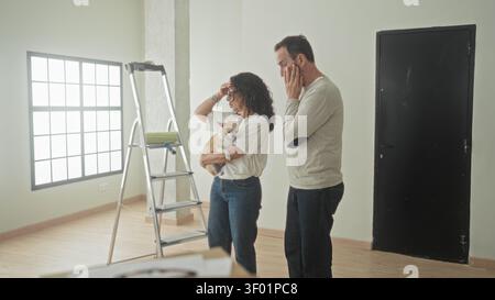 Frau, die einen kleinen chihuahua neben einer Metallleiter hält, während der Mann Hände auf Hüften in der Nähe der schwarzen Tür im Gebäude steht; Bedenken Sie die Entscheidung. Stockfoto