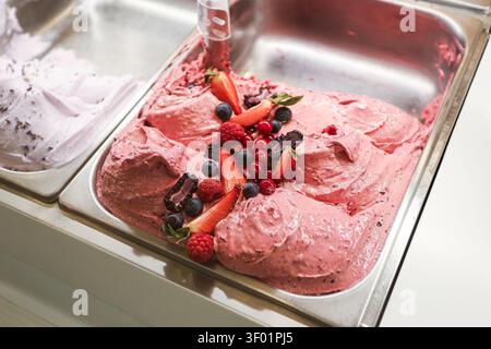 Beeren-Eiscreme und Frucht-Sorbet im Metallbehälter. Gefrorenes Dessert-Hintergrund für sommerliche Erfrischung, süße Speisen, farbenfrohe Geschmacksrichtungen und kalte Leckereien. Stockfoto