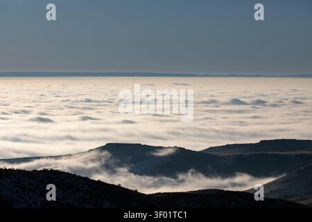 Schneebedeckte Berggipfel durchstechen Wolkenschichten Stockfoto