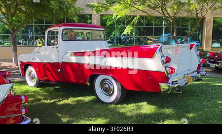 Ein klassischer zweifarbiger, rot-weißer Oldtimer-Pickup, der während einer sonnigen Autoshow auf einem Rasen geparkt wurde. Stockfoto