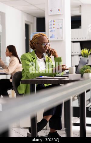 Unternehmensberaterin spricht mit ernstem Ausdruck auf dem Handy und bespricht Details zur Geschäftsstrategie mit dem Kunden. Zielgerichtete professionelle Frau, die einem Kollegen ein Projektgespräch gibt. Stockfoto