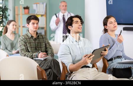 Die Studenten hören Vorlesungen im Klassenzimmer, mit einem Medizinprofessor im Hintergrund Stockfoto
