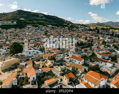 Blick aus der Vogelperspektive auf das historische Dorf mit traditionellen Steinhäusern, roten Ziegeldächern und einer prominenten Kirche, eingebettet in die Hügel von Pano Lefkara, Stockfoto