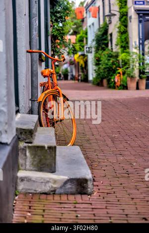 Orange Fahrrad, das in der Bentinckstraat im 7straßen-Viertel von Arnhem, Niederlande, geparkt ist. Stockfoto