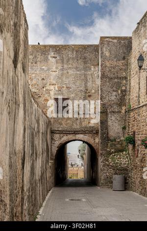 Marokko - Tanger - Kasbah - Ein schmaler Durchgang durchquert dicke alte Steinmauern, eingerahmt von einem hohen spitzen Bogentor am anderen Ende, das sich öffnet Stockfoto